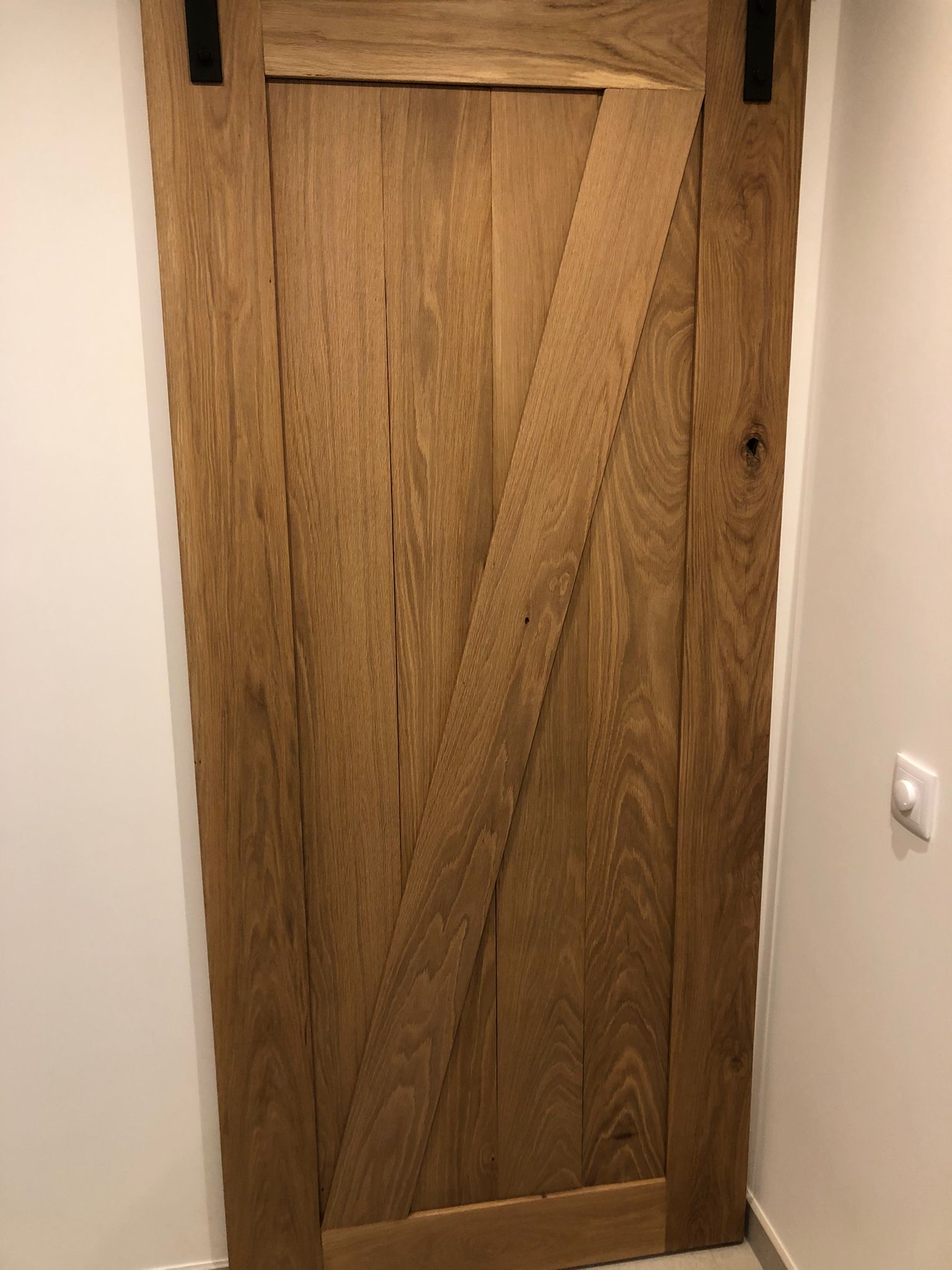 Handmade solid oak sliding door on a black steel rail