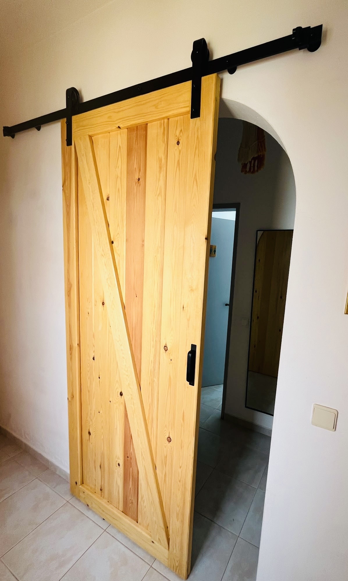 Handmade pine sliding door open across a rounded interior doorway